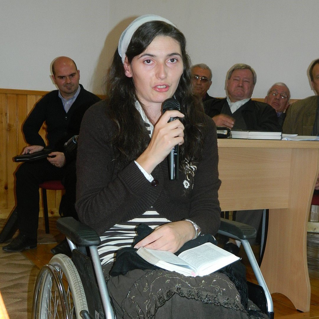 Vrouw in een rolstoel spreekt met een microfoon tijdens een voorlichtingsbijeenkomst
